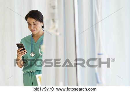 Stock Image - Mixed race nurse using cell phone in hospital. Fotosearch