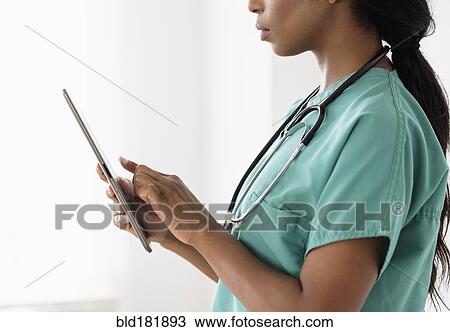 Stock Image - Mixed race nurse using digital tablet. Fotosearch