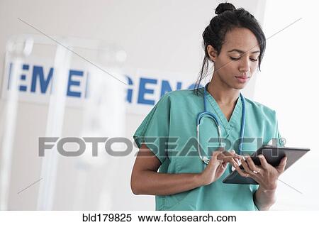 Stock Photography - Mixed race nurse using digital tablet in hospital. Fotosearch