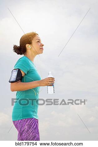 Mixed race runner drinking water outdoors View Large Photo Image Picture - Mixed race runner drinking water outdoors. Fotosearch