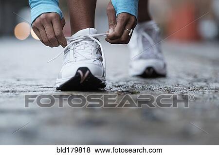 Stock Photo - Mixed race runner tying shoelaces. Fotosearch
