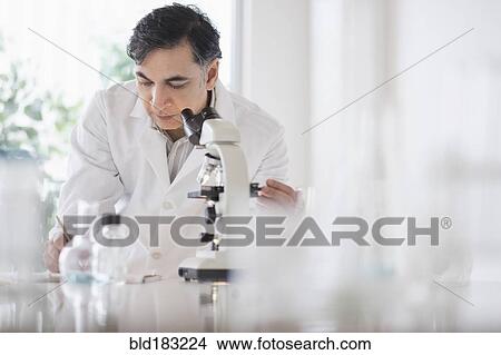 Picture - Mixed race scientist using microscope in laboratory. Fotosearch
