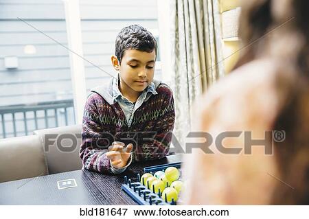 Stock Photo - Mixed race siblings playing board game. Fotosearch