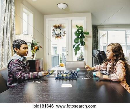 Stock Photograph - Mixed race siblings playing board game. Fotosearch