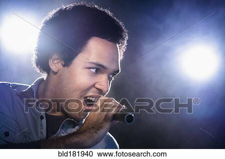 Stock Image - Mixed race singer performing on stage. Fotosearch