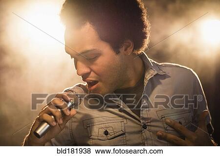 Stock Photo - Mixed race singer performing on stage. Fotosearch