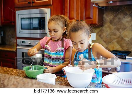 Mixed race sisters cooking in kitchen View Large Photo Image Stock Photograph - Mixed race sisters cooking in kitchen. Fotosearch