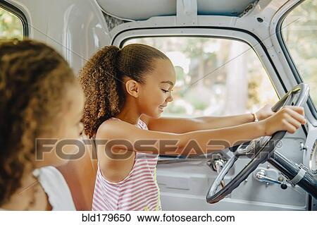 Stock Image - Mixed race sisters driving in car. Fotosearch