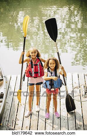 Mixed race sisters holding oars at lake View Large Photo Image Stock Image - Mixed race sisters holding oars at lake. Fotosearch