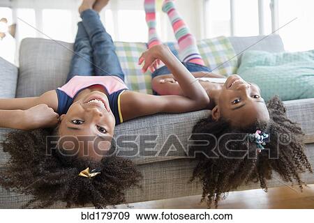 Mixed race sisters laying on sofa View Large Photo Image Stock Photo - Mixed race sisters laying on sofa. Fotosearch