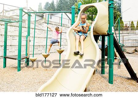 Stock Photo - Mixed race sisters playing on playground. Fotosearch