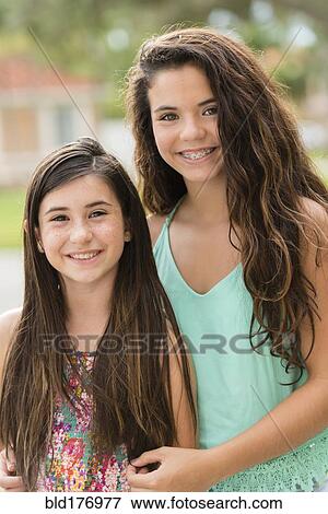 Stock Photo - Mixed race sisters smiling outdoors. Fotosearch