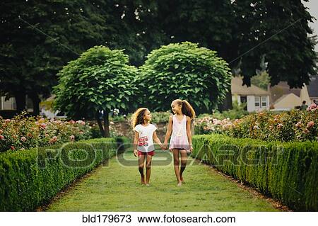 Mixed race sisters walking in garden View Large Photo Image Stock Image - Mixed race sisters walking in garden. Fotosearch
