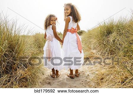 Mixed race sisters walking on beach View Large Photo Image Stock Image - Mixed race sisters walking on beach. Fotosearch