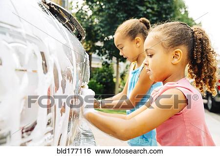 Stock Photograph - Mixed race sisters washing car. Fotosearch