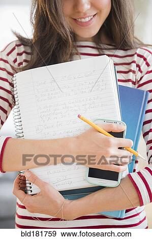 Mixed race student holding homework and cell phone View Large Photo Image Stock Photo - Mixed race student holding homework and cell phone. Fotosearch