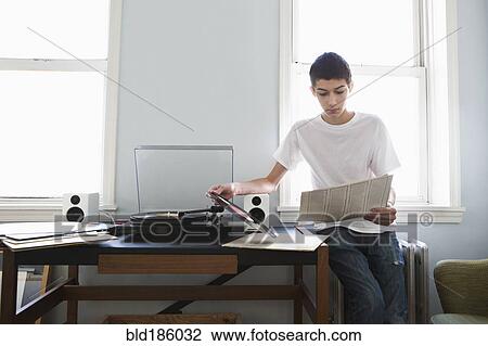 Stock Image - Mixed race teenage boy listening to records. Fotosearch
