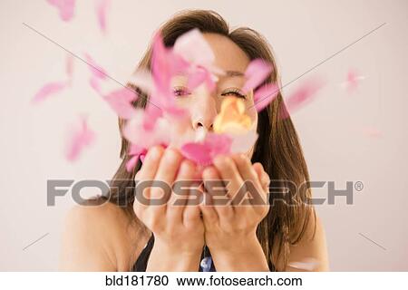 Stock Image - Mixed race woman blowing confetti. Fotosearch