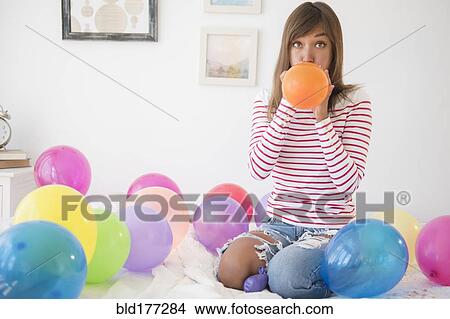 Picture - Mixed race woman blowing up balloons. Fotosearch