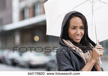 Mixed race woman carrying umbrella outdoors View Large Photo Image Stock Image - Mixed race woman carrying umbrella outdoors. Fotosearch