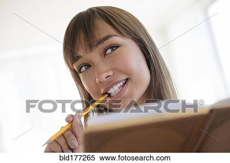 Mixed race woman chewing pencil and reading View Large Photo Image Stock Photography - Mixed race woman chewing pencil and reading. Fotosearch