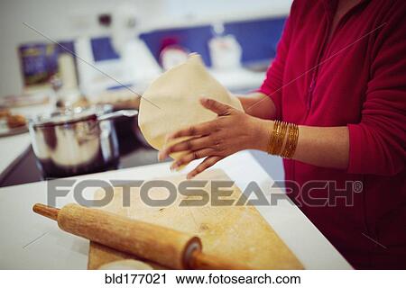 Stock Image - Mixed race woman cooking in kitchen. Fotosearch