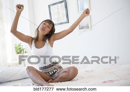 Stock Photo - Mixed race woman dancing on bed. Fotosearch