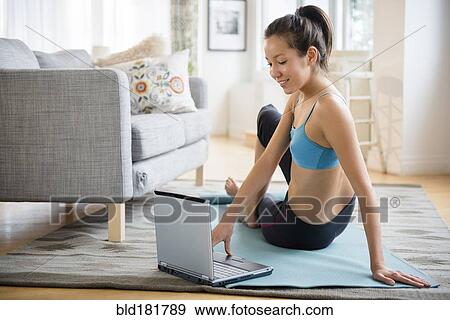 Mixed race woman doing yoga video in living room View Large Photo Image Stock Photo - Mixed race woman doing yoga video in living room. Fotosearch