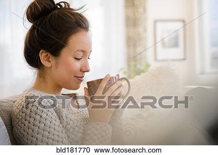 Mixed race woman drinking coffee on sofa View Large Photo Image Stock Image - Mixed race woman drinking coffee on sofa. Fotosearch
