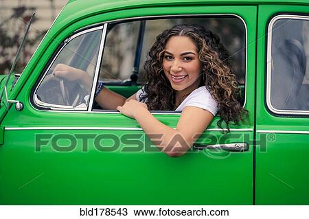 Stock Image - Mixed race woman driving green car. Fotosearch