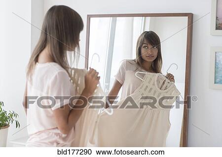 Mixed race woman examining dress in mirror View Large Photo Image Stock Image - Mixed race woman examining dress in mirror. Fotosearch