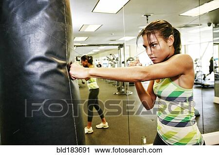 Mixed race woman hitting punching bag in gymnasium View Large Photo Image Stock Image - Mixed race woman hitting punching bag in gymnasium. Fotosearch