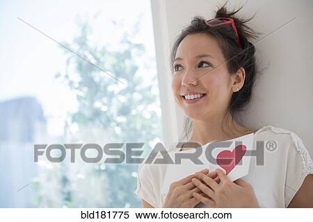 Stock Photography - Mixed race woman holding Valentine card. Fotosearch