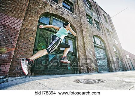 Picture - Mixed race woman jogging on sidewalk. Fotosearch
