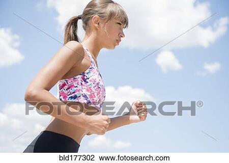 Mixed race woman jogging under blue sky View Large Photo Image Stock Image - Mixed race woman jogging under blue sky. Fotosearch