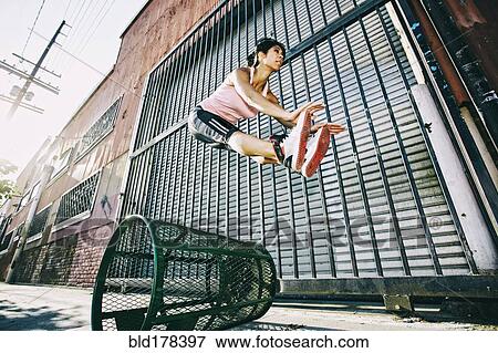 Mixed race woman jumping over trash can View Large Photo Image Stock Photo - Mixed race woman jumping over trash can. Fotosearch