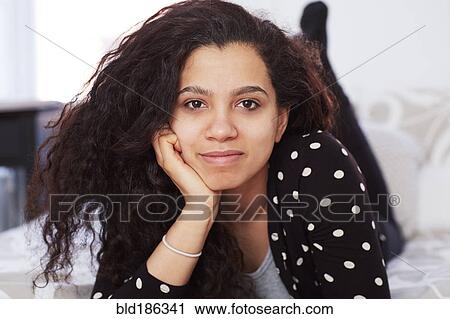 Stock Image - Mixed race woman laying on bed. Fotosearch