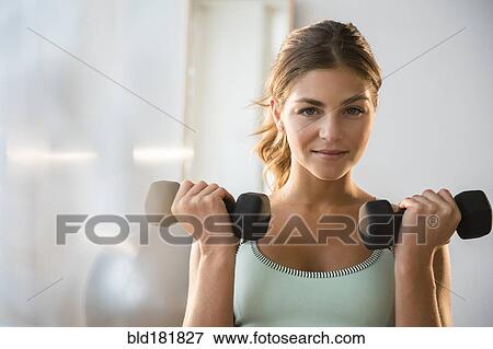 Stock Photo - Mixed race woman lifting weights in gym. Fotosearch