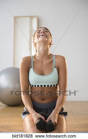 Stock Photo - Mixed race woman lifting weights in gym. Fotosearch