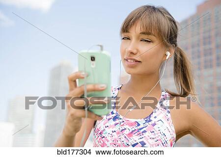 Picture - Mixed race woman listening to earbuds. Fotosearch