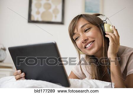 Mixed race woman listening to headphones View Large Photo Image Stock Photo - Mixed race woman listening to headphones. Fotosearch