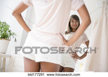 Stock Image - Mixed race woman looking in mirror. Fotosearch