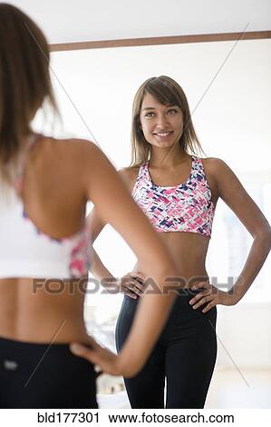 Stock Image - Mixed race woman looking in mirror. Fotosearch