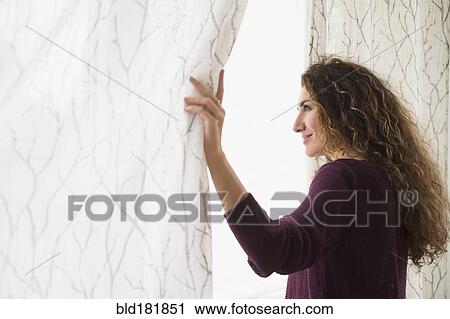 Mixed race woman looking out window curtain View Large Photo Image Stock Image - Mixed race woman looking out window curtain. Fotosearch