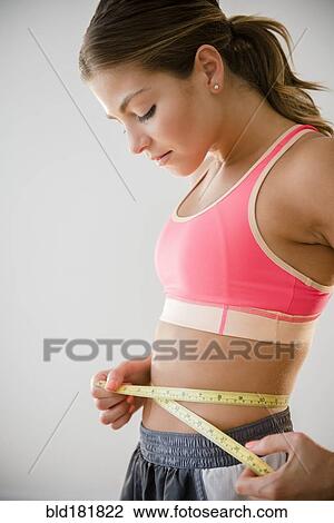 Mixed race woman measuring her waist View Large Photo Image Stock Image - Mixed race woman measuring her waist. Fotosearch