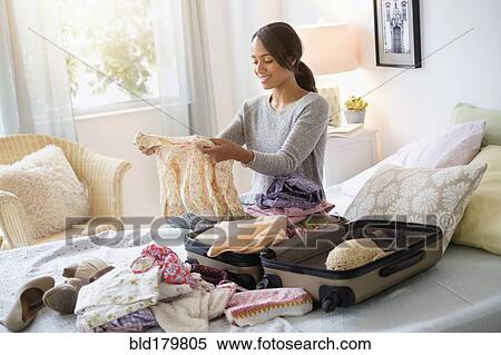 Mixed race woman packing suitcase in bed View Large Photo Image Stock Photography - Mixed race woman packing suitcase in bed. Fotosearch