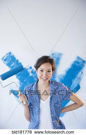 Stock Photo - Mixed race woman painting wall. Fotosearch