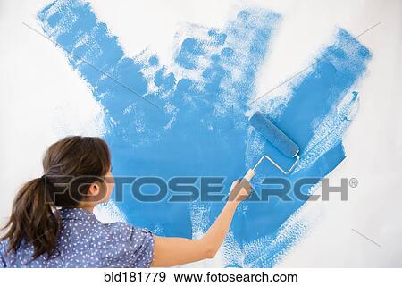 Stock Photo - Mixed race woman painting wall. Fotosearch