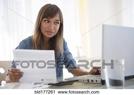 Mixed race woman paying bills on laptop View Large Photo Image Stock Image - Mixed race woman paying bills on laptop. Fotosearch