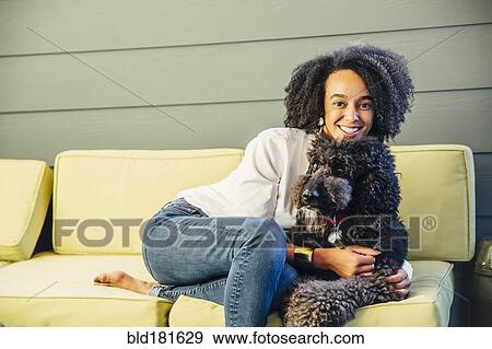 Mixed race woman petting dog on sofa View Large Photo Image Stock Photo - Mixed race woman petting dog on sofa. Fotosearch